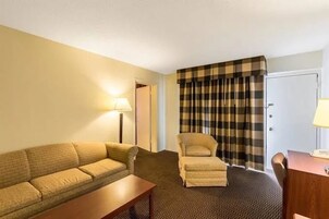 Una habitación de hotel con un sofá, un sillón y una pequeña mesa.