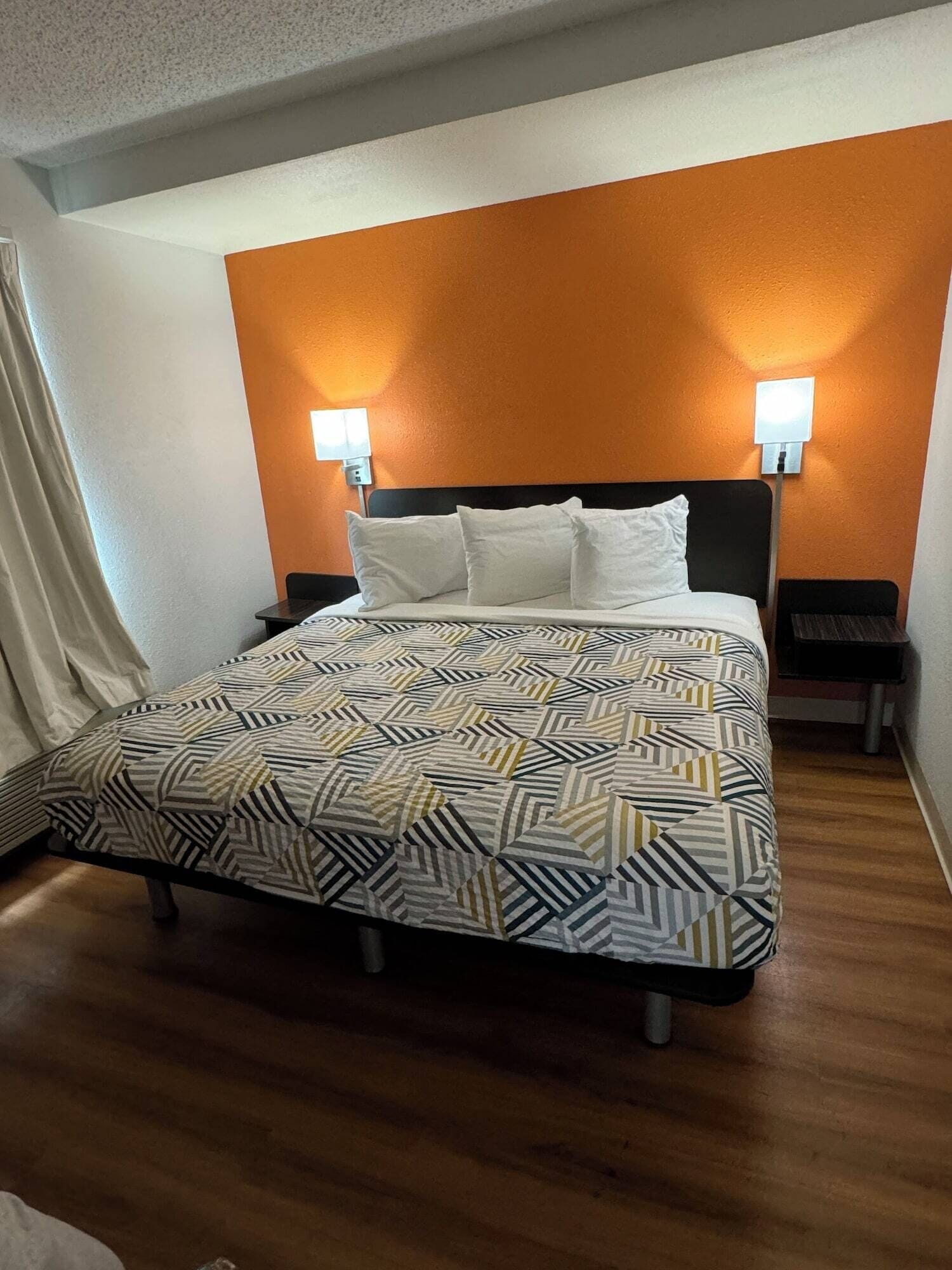 A hotel room with a bed, two bedside tables, and a nightstand.