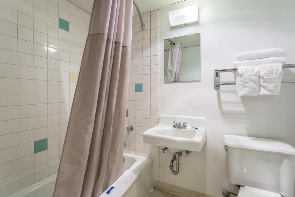 Un baño con bañera, lavamanos, espejo e inodoro.