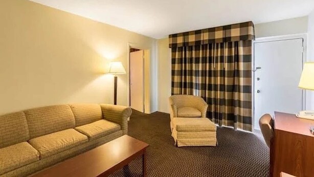 Une chambre d’hôtel avec un canapé, un fauteuil et un bureau avec une lampe.
