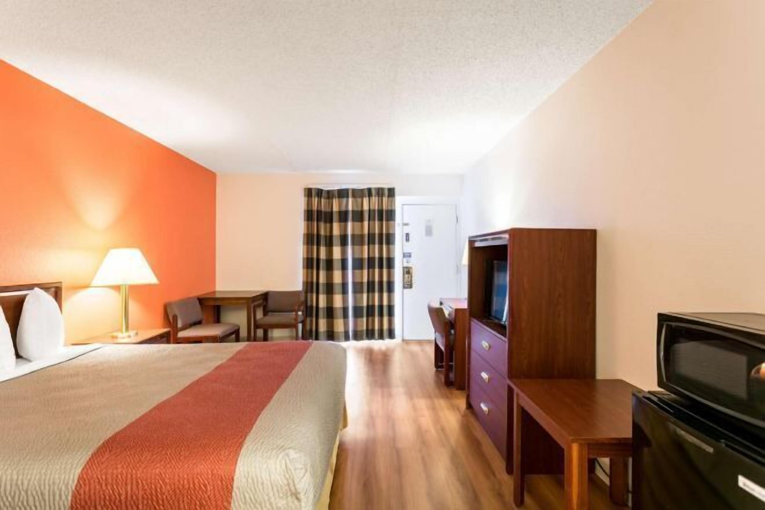 A hotel room with a bed, a desk, a television, and a wardrobe.