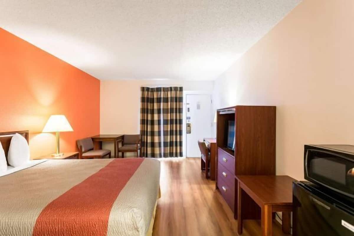 A hotel room with a bed, a desk, a television, and a wardrobe.