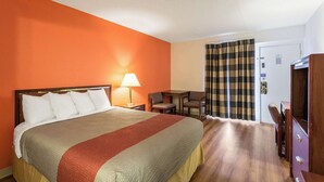 Une chambre d’hôtel avec un grand lit, un bureau avec une chaise, une télévision et une porte avec un rideau.