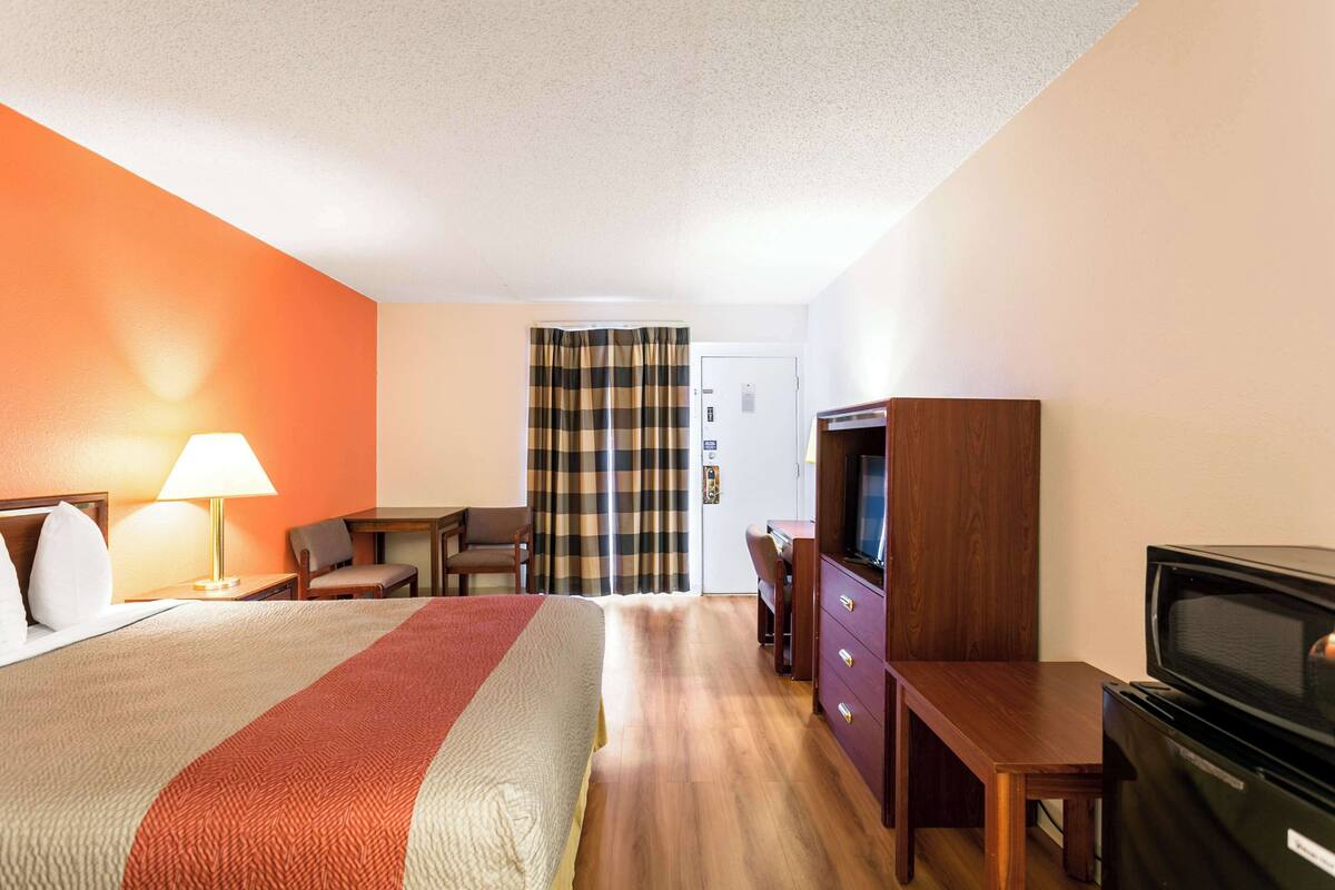 A hotel room with a bed, a desk, a television, and a wardrobe.