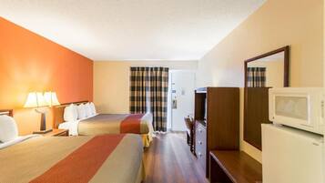 Habitación de hotel con dos camas, un escritorio, un aparador, un microondas y un televisor.