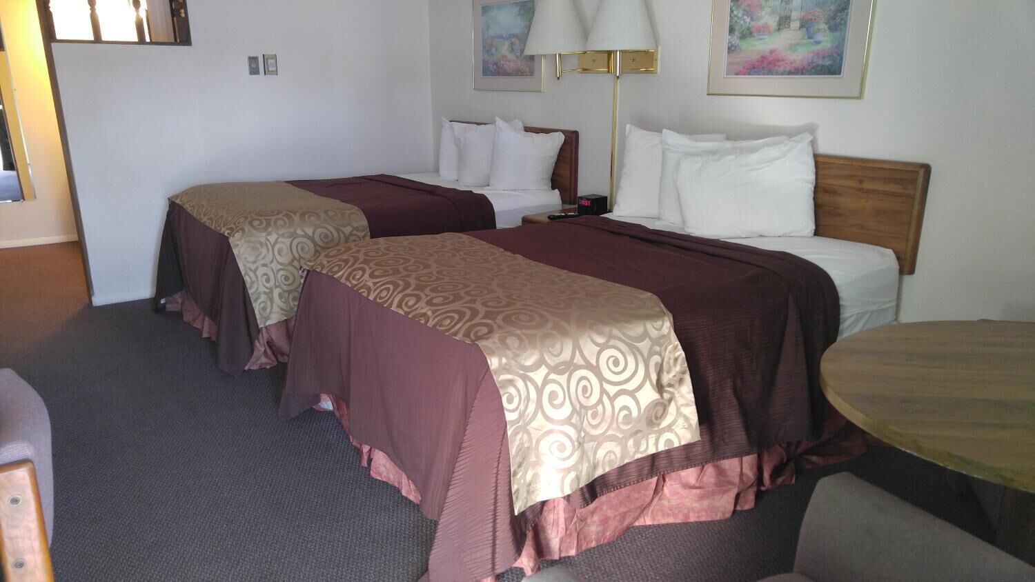 Habitación de hotel con dos camas, una mesa redonda y una lámpara.