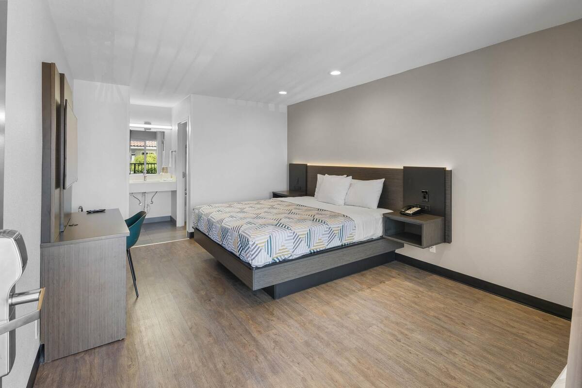 Quarto moderno com cama, mesa de cabeceira e escrivaninha com cadeira.
