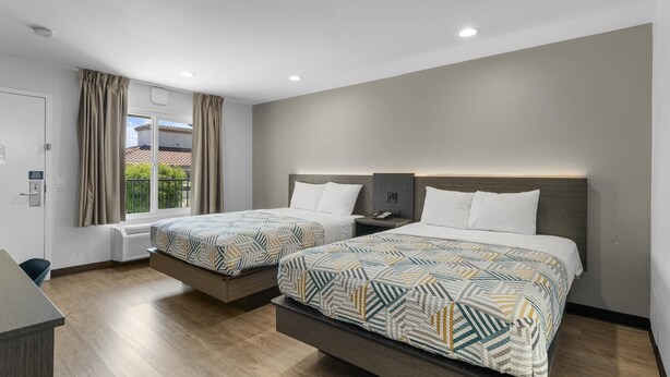 Ein modernes Hotelzimmer mit zwei Betten, einem Balkon und einem Schreibtisch.