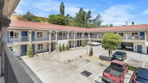Ein Motel mit rotem Ziegeldach, mehreren Balkonen und einem Parkplatz mit einigen Fahrzeugen.