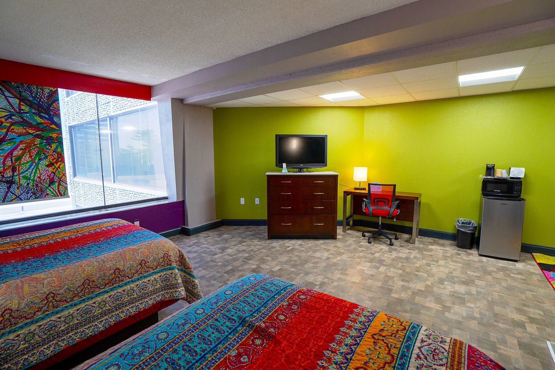 A hotel room with two beds, a desk with a computer, a television, and a microwave.
