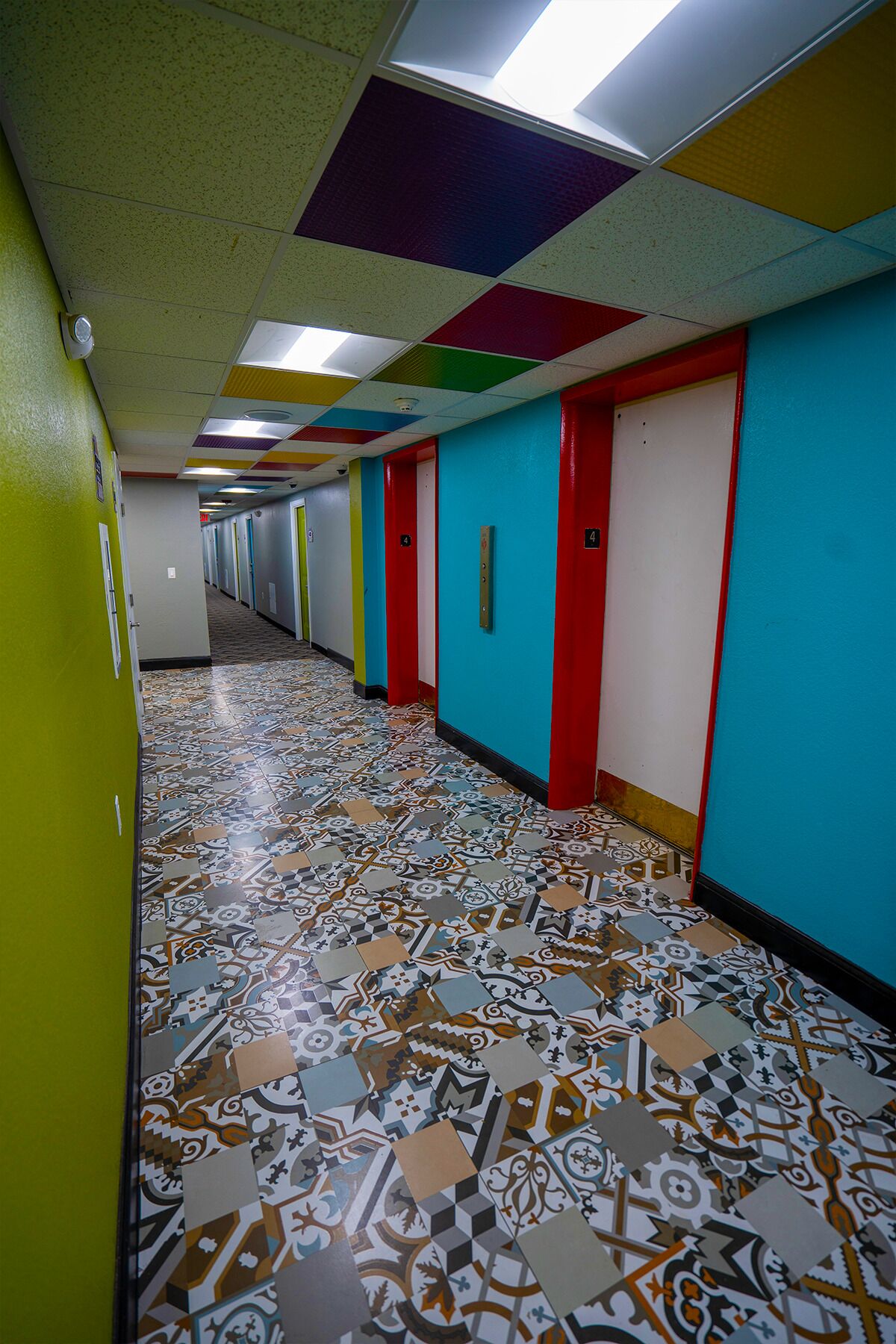 A brightly colored hallway with patterned floor tiles and numbered doors.
