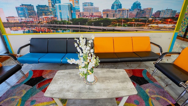 A seating area with a cityscape mural, a table with a vase of flowers, and colorful rugs. - Philly Inn & Suites (Philadelphia)
