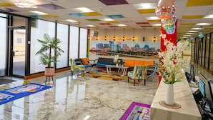A hotel lobby with a cityscape view, colorful ceiling tiles, and a reception desk with a vase of flowers. - Philly Inn & Suites (Philadelphia)
