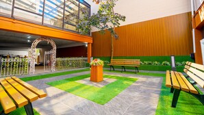 An indoor courtyard with benches, a planter with flowers, and a glass ceiling. - Philly Inn & Suites (Philadelphia)