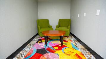 Un pasillo con dos sillones verdes y una mesita redonda, cubierto con un colorido estampado geométrico.