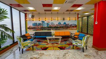 A modern lounge area with a cityscape view, colorful ceiling, and a mix of seating options.