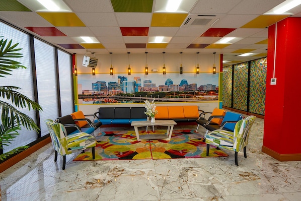 A modern lounge area with a cityscape view, colorful ceiling, and a mix of seating options.