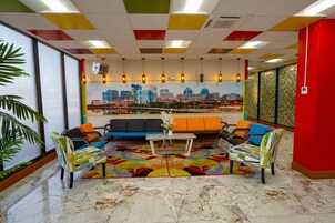 A modern lounge area with a cityscape view, colorful ceiling, and a mix of seating options.