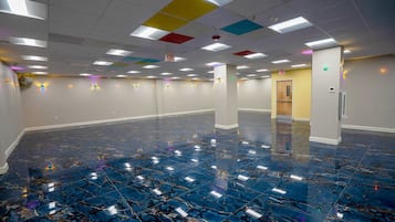 A spacious room with a polished marble floor, multiple exit signs, and a door leading to another area.