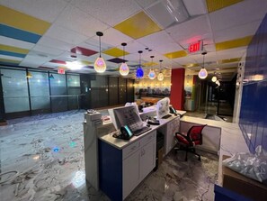 A hotel reception area with a marble floor, a desk with a computer and telephone, and colorful hanging lights.