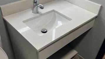 A bathroom with a white sink, a mirror above it, and a toilet to the left.