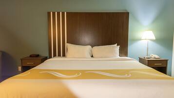 Una camera d'hotel con un letto grande, due comodini e una lampada.