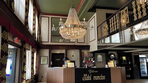 Un hall d'hôtel comprenant un lustre, un comptoir d'accueil et un distributeur automatique.