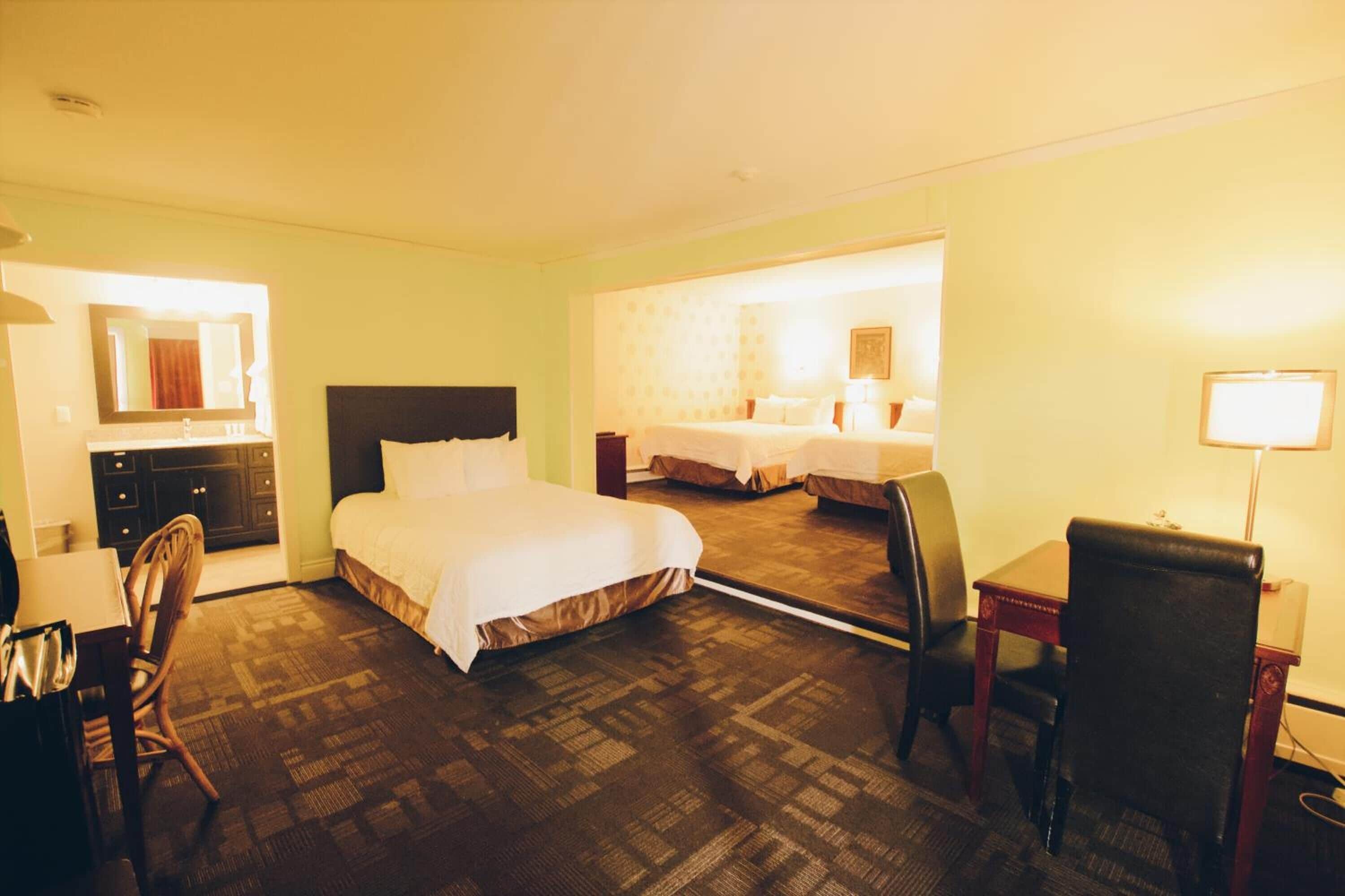 Une chambre d’hôtel avec un grand lit, un bureau, une chaise et un miroir.