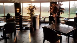 Un restaurant doté de grandes fenêtres, d’un bar et de plusieurs tables et chaises.