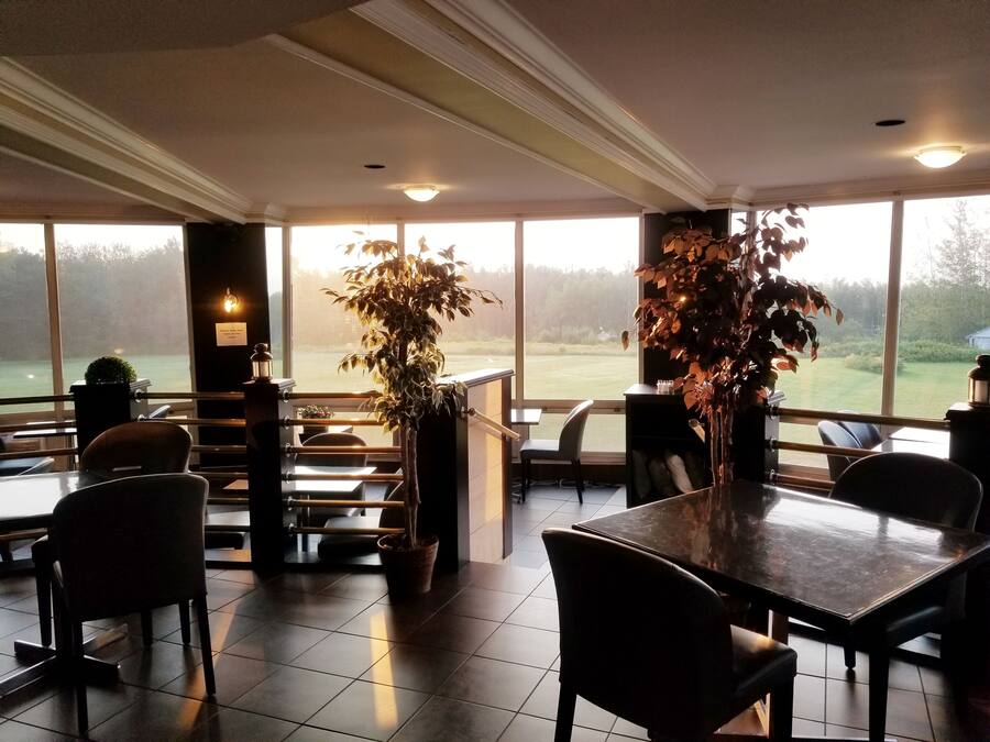 A restaurant with large windows, a bar area, and several tables and chairs.