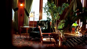A cozy room with a leather armchair, a wooden chair, a small round table, and a potted plant. - The Union Club of British Columbia (Victoria)