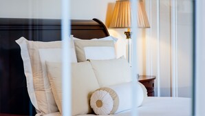 A neatly made bed with multiple pillows and a wooden headboard. - The Union Club of British Columbia (Victoria)