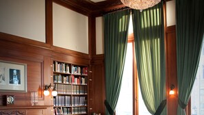 A library with a large bookcase, a fireplace, and a chandelier. - The Union Club of British Columbia (Victoria)