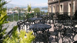 A terrace with outdoor seating, a view of a river, and a building with a brick facade. - The Union Club of British Columbia (Victoria)