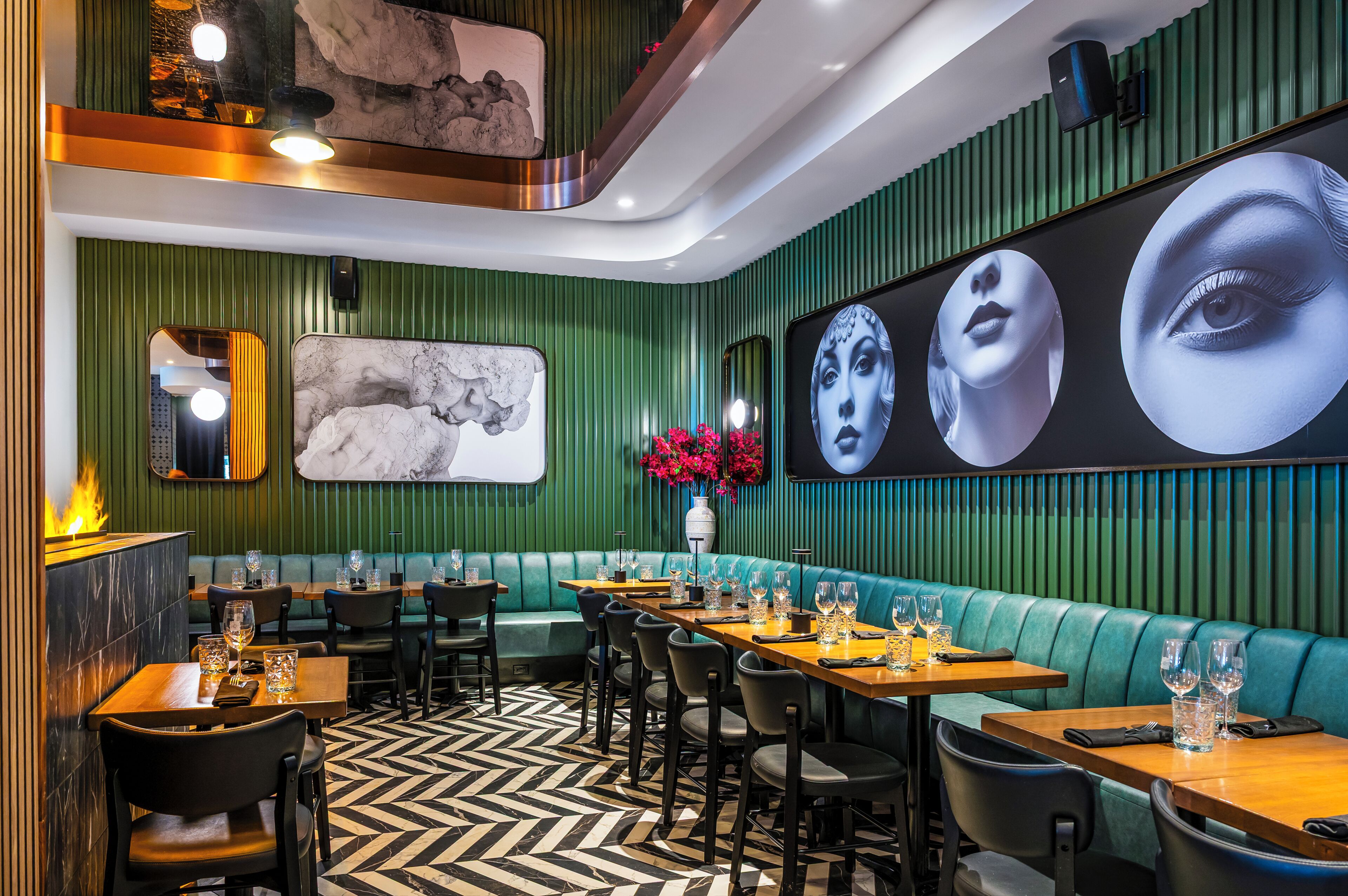 Restaurante com paredes verdes, arte em mármore e chão com padrão em preto e branco.