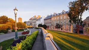 Un sentier mène à une rangée de bâtiments historiques en pierre, avec un lampadaire et des jardins bien entretenus.