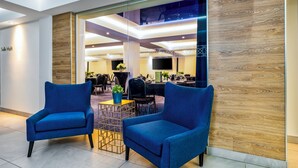 Un hall d’entrée moderne avec deux fauteuils bleus, une cloison en verre et un mur décoratif en bois.