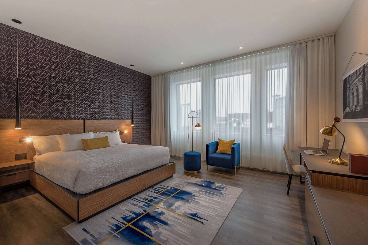 A modern bedroom with a large bed, a desk, and a chair.