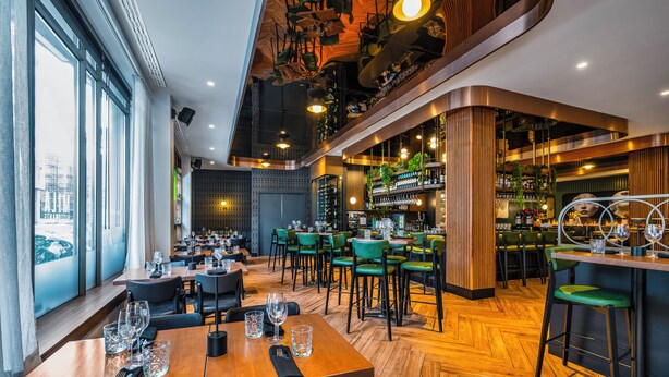 Un restaurant doté d’un plancher en bois, de chaises vertes et d’un coin bar décoré avec des vélos.