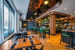 Un restaurante con suelo de madera, sillas verdes y una zona de bar con una decoración de bicicleta.