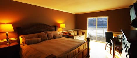 A bedroom with a large bed, bedside lamps, a sofa, a desk, and a television.