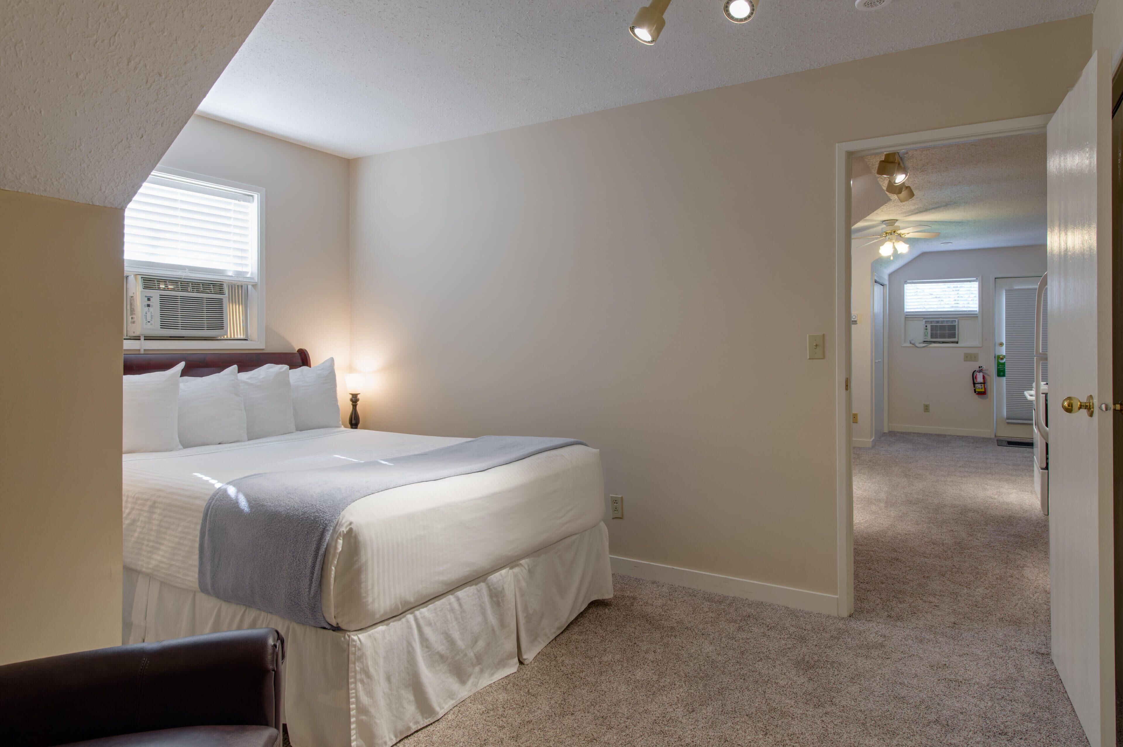 A bedroom with a large bed, a ceiling fan, and a window with blinds.