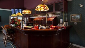 A bar area with a wooden counter, hanging lamps, and a floral arrangement. - South Thompson Inn & Conference Centre (Kamloops)