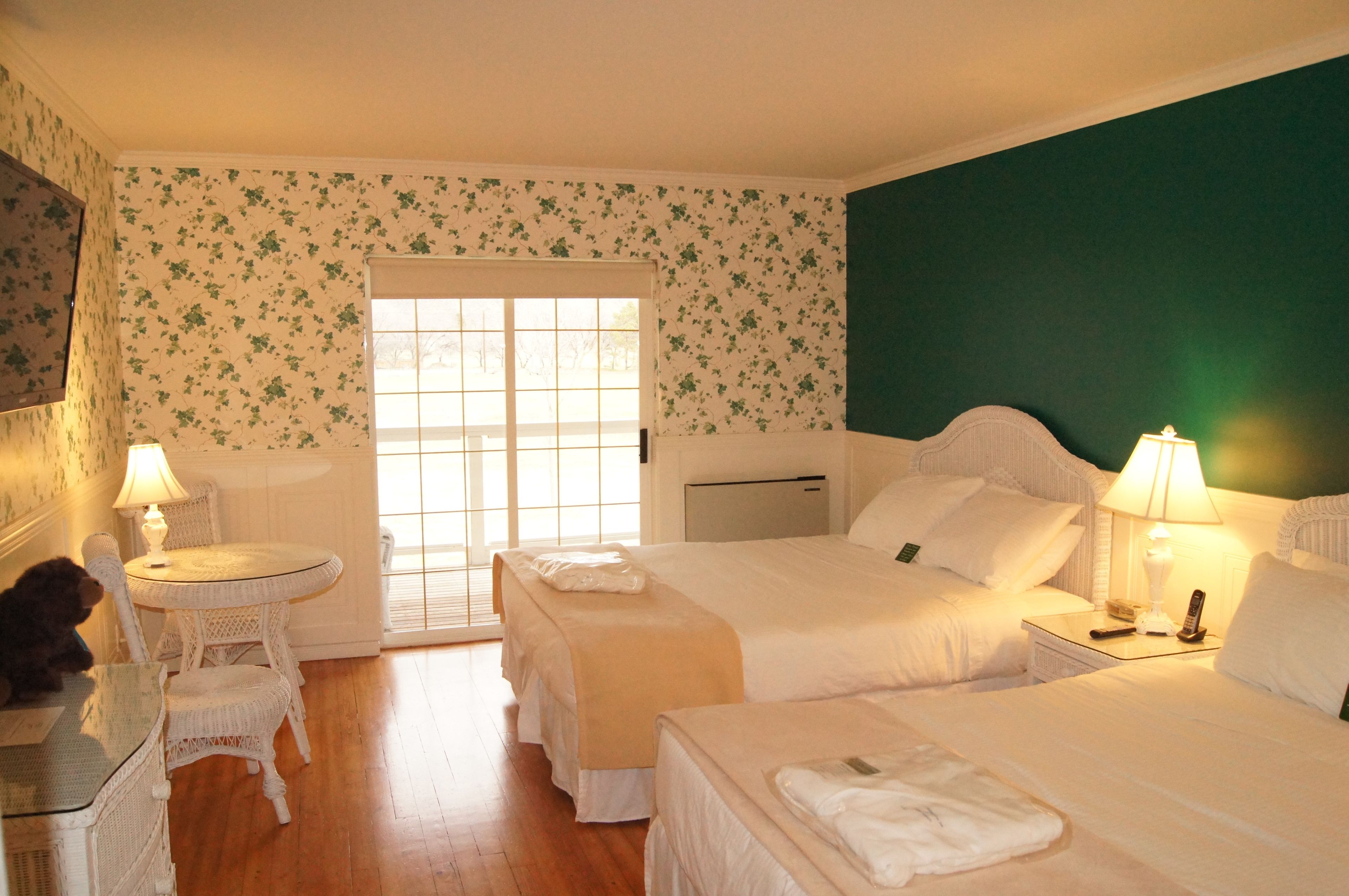 A hotel room with two beds, a small table, a chair, and a desk.