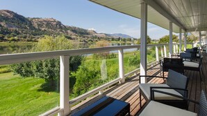 A covered outdoor deck with a view of a lake and hills. - South Thompson Inn & Conference Centre (Kamloops)