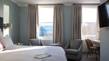 Una habitación de hotel con una cama, dos sillas, un escritorio y un televisor.