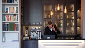 Un espace bar équipé d’une machine à café, d’étagères remplies de livres et d’un barman.