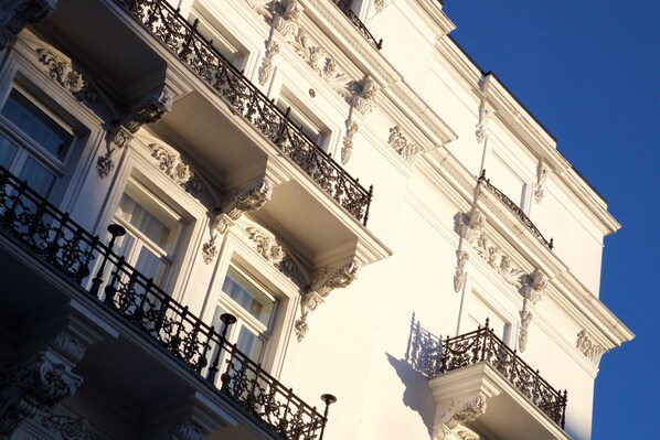 Un immeuble à plusieurs étages, doté de balcons richement décorés et de détails architecturaux classiques.