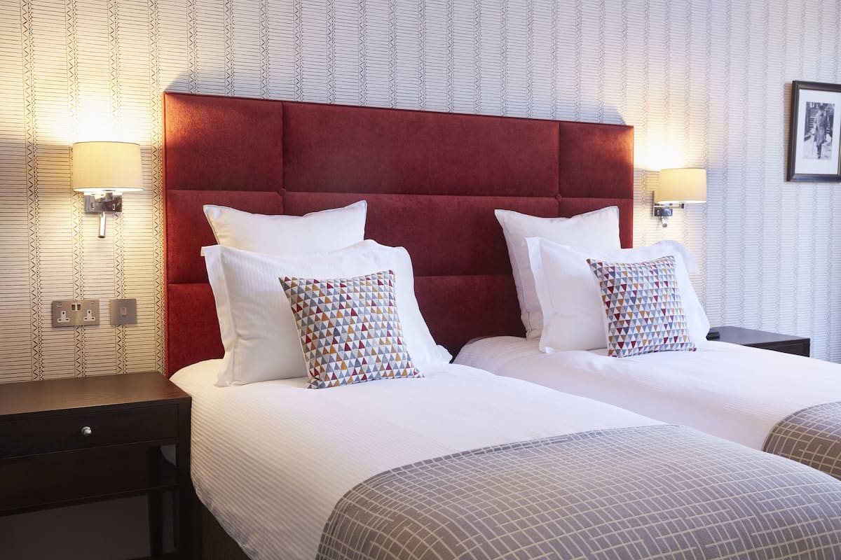 Una habitación de hotel con una cama grande, dos mesitas de noche y un cabecero rojo.
