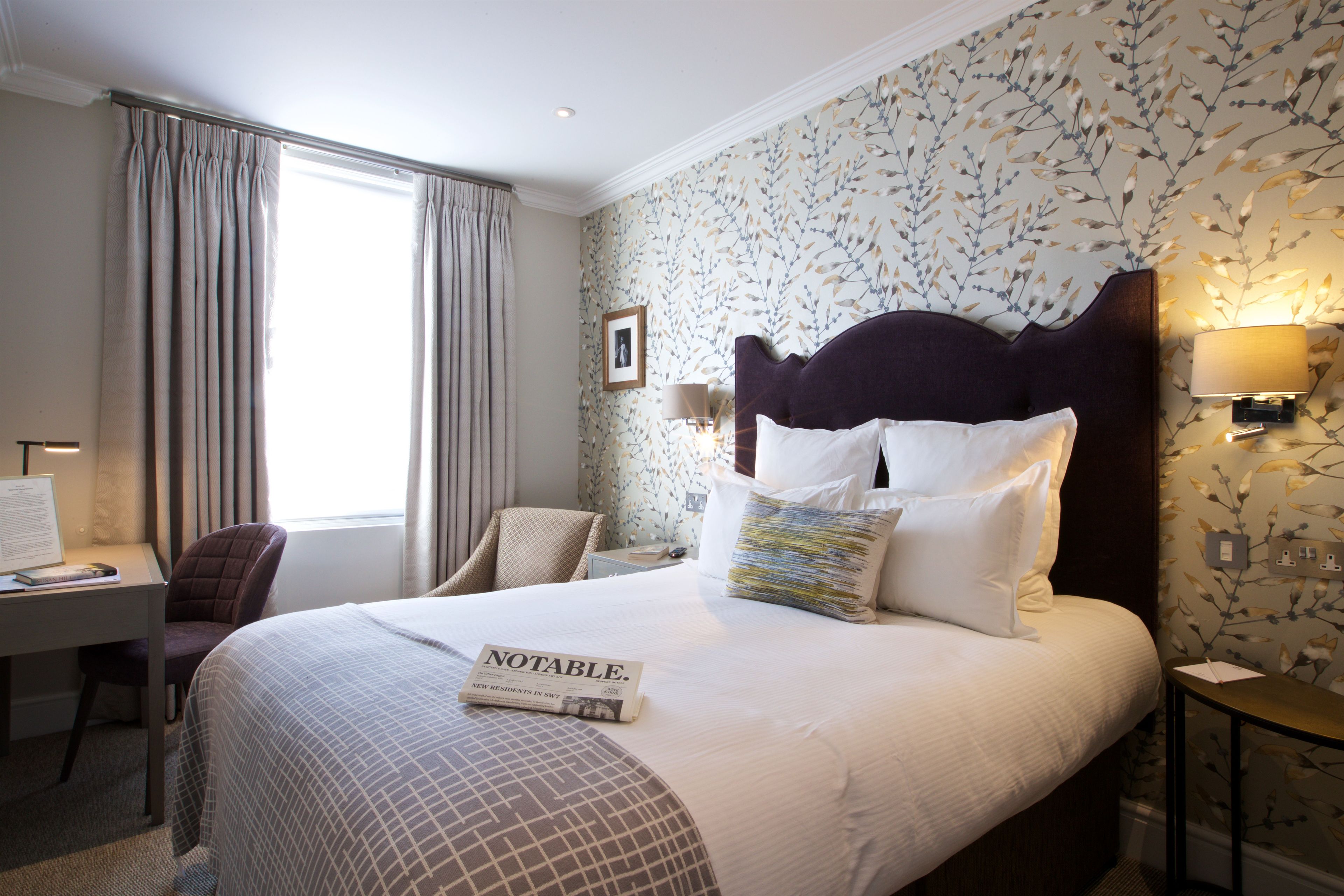 A hotel room with a large bed, a desk, and a chair.